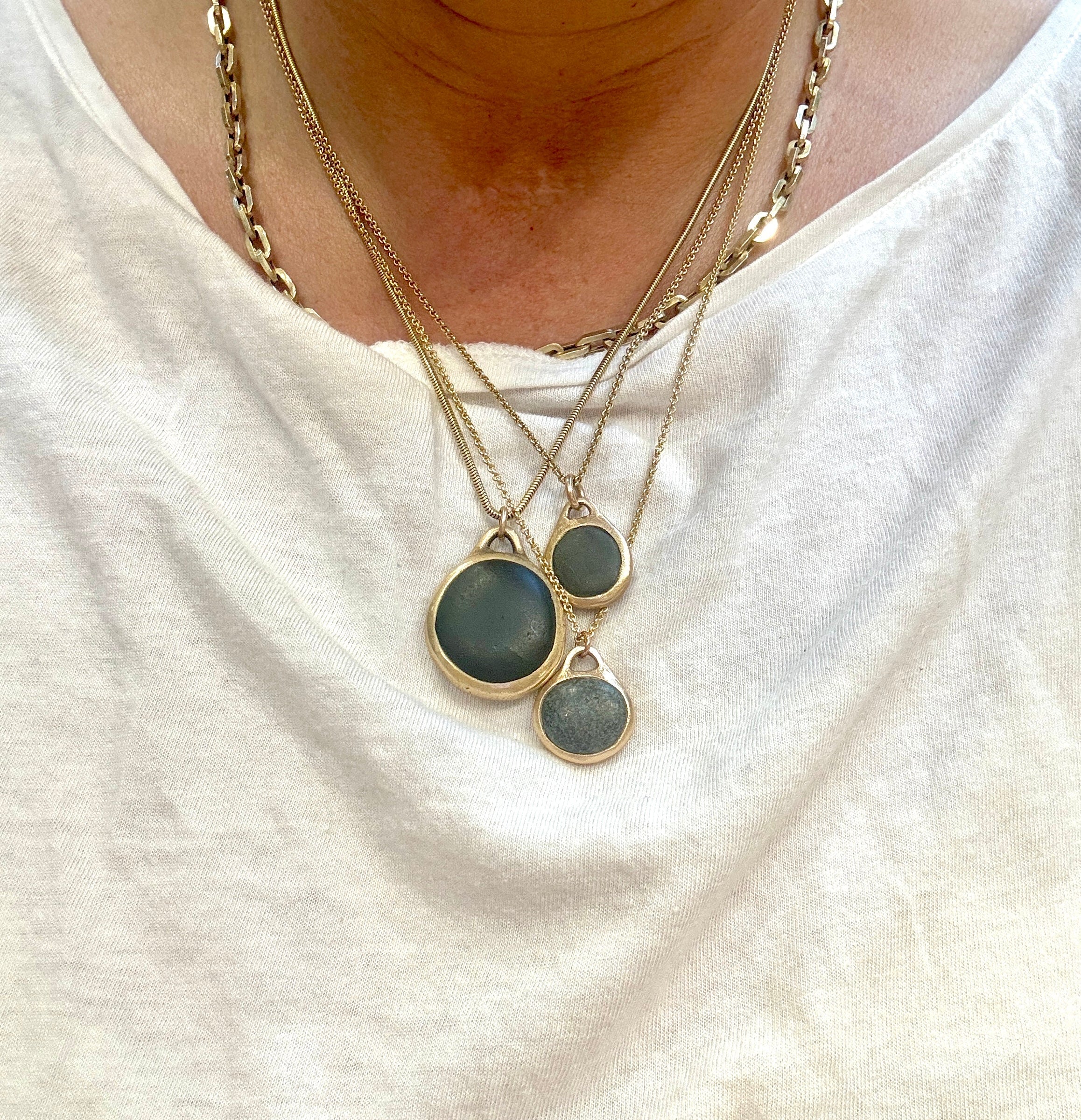 Model wearing three smooth dark pebble necklaces pebblebelly