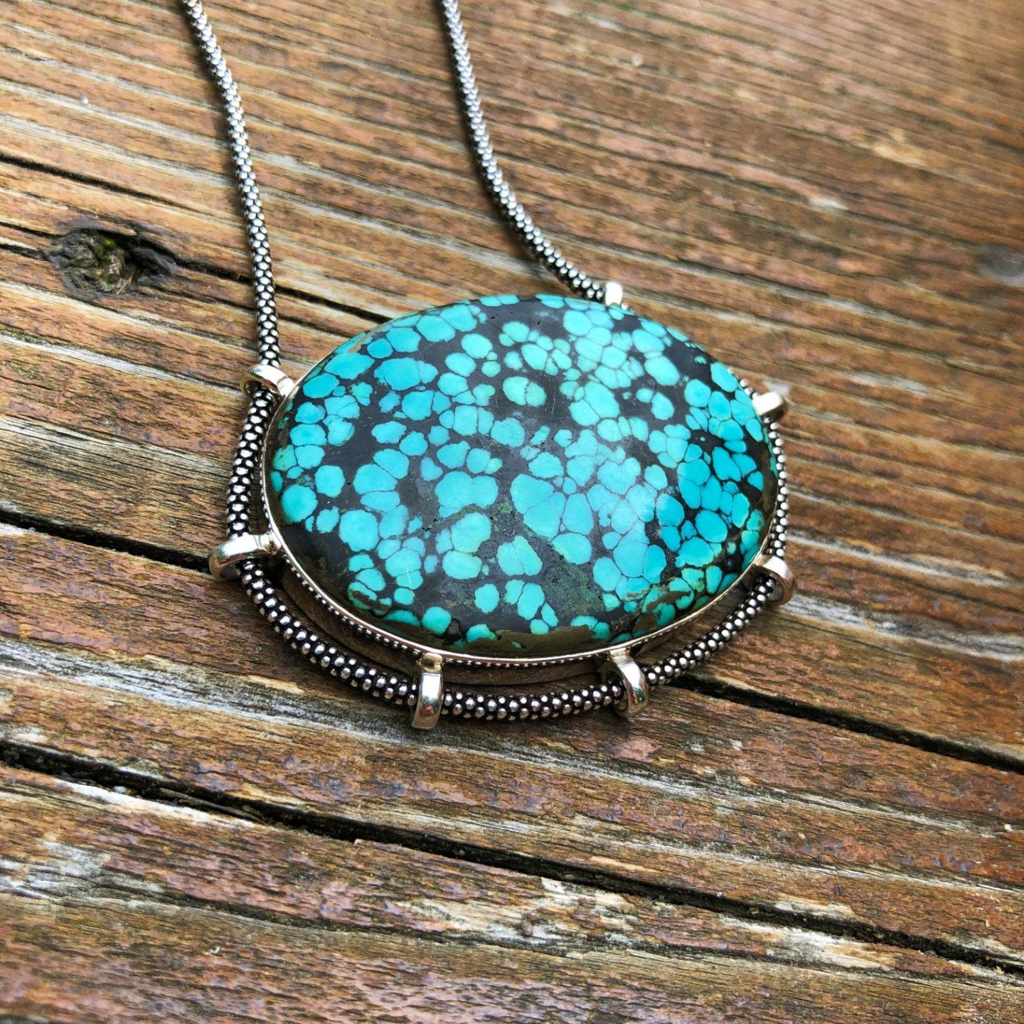 authentic turquoise horizontal oval shaped pendant on unique setting weathered driftwood background