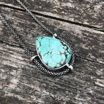 Load image into Gallery viewer, authentic turquoise horizontal teardrop shaped pendant on unique Sterling Silver setting. on weathered driftwood background. Sterling Silver Chain
