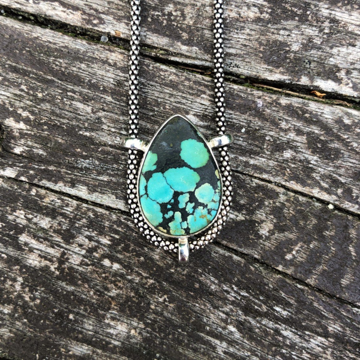authentic turquoise tear shaped pendant on unique setting  with beautiful oxidized Sterling Silver chainweathered driftwood background