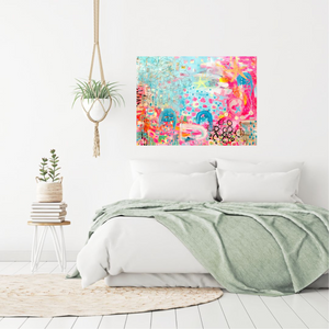 vibrant, happy abstract painting with pinks and blues and stars and hearts and an ocean vibe over a bed with white bedding in an airy white room